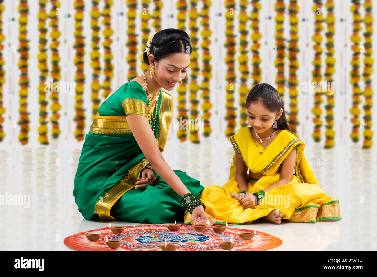 Woman arranging diyas on a rangoli Stock Photo - Alamy