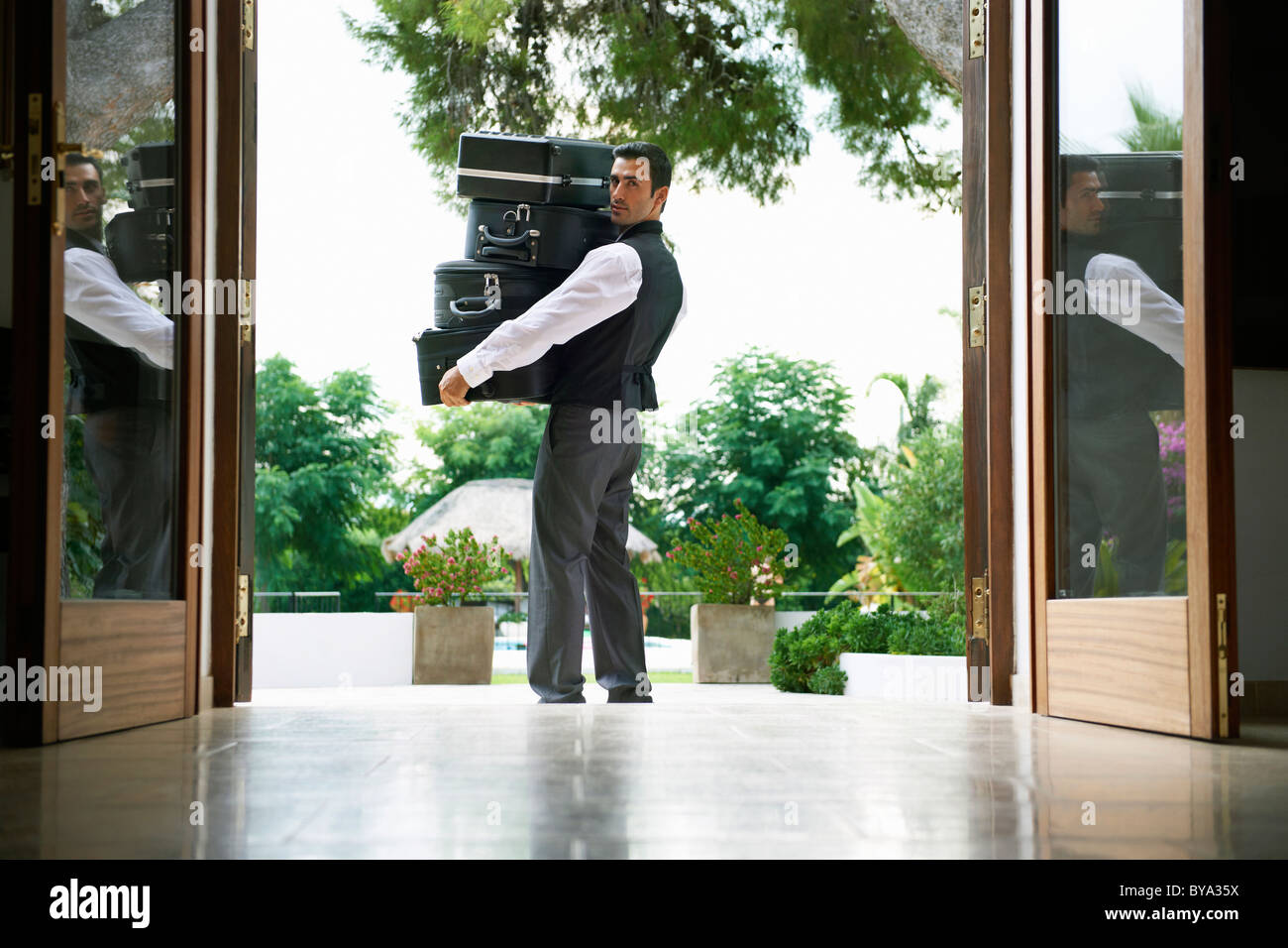 Man carrying suitcases into hotel Stock Photo