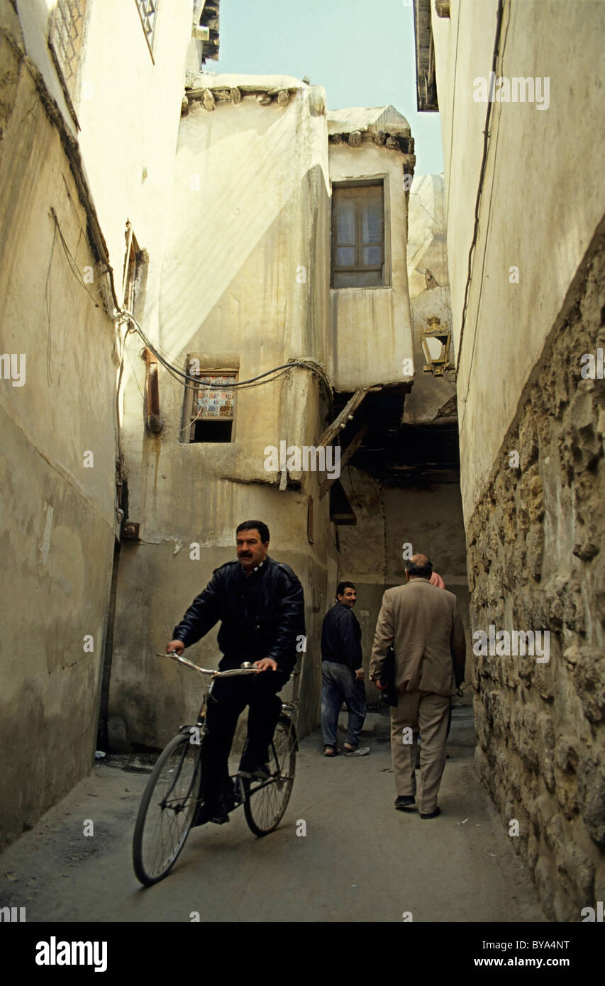 Man cycling through the narrow streets of the old town, Damascus, Syria. Stock Photo