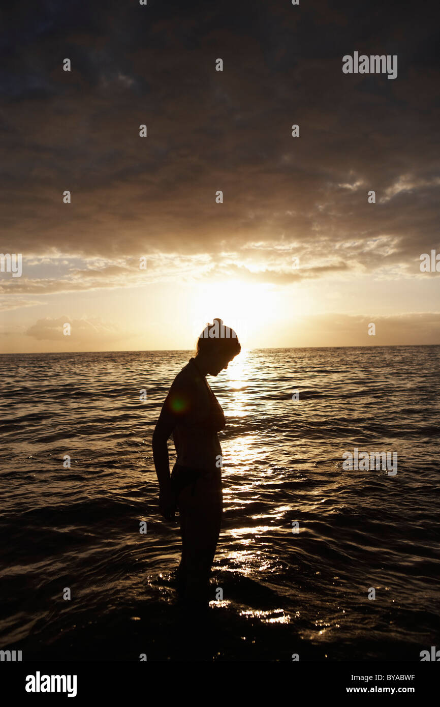 Woman standing in sea by sunset Stock Photo - Alamy