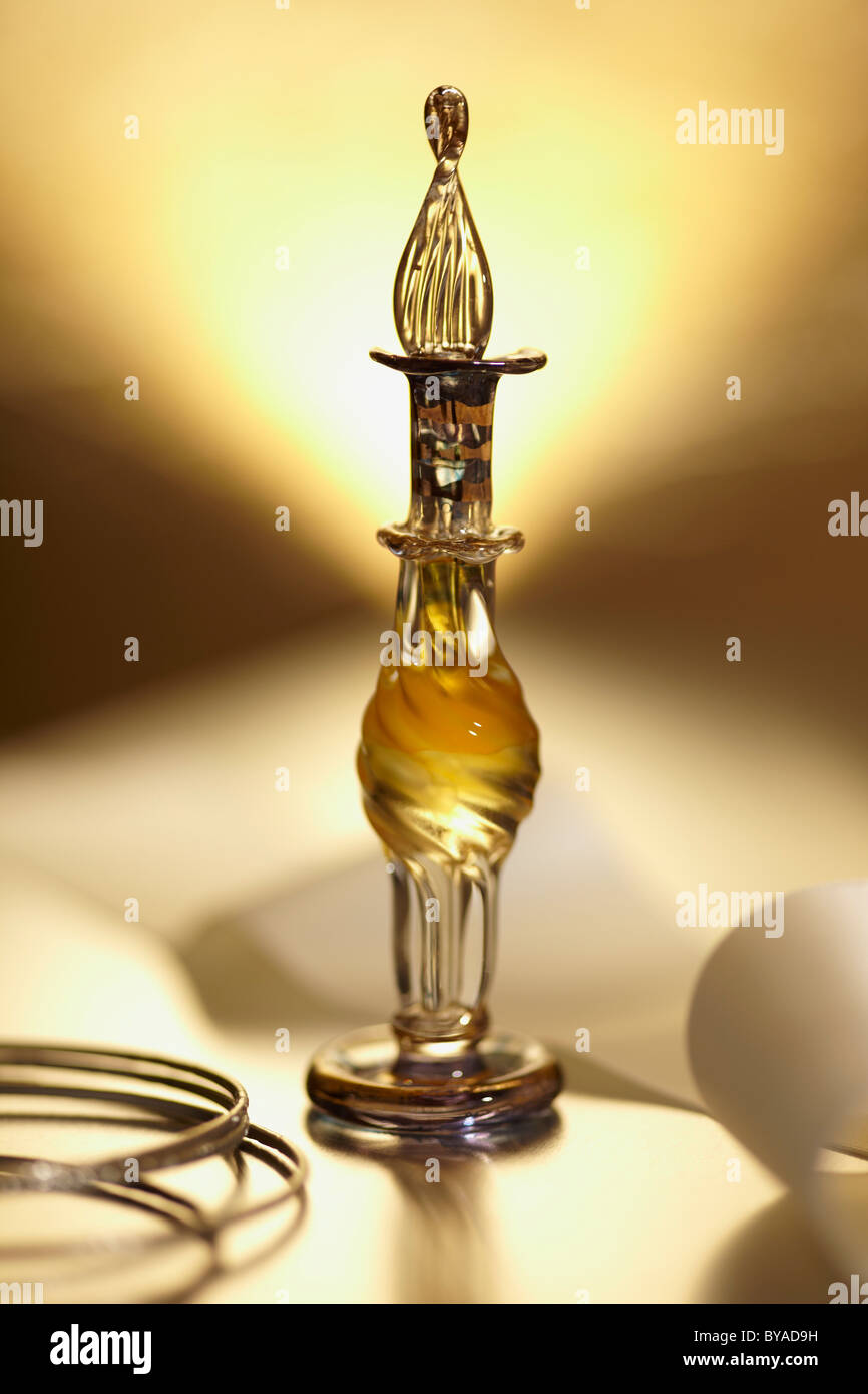 Perfume bottle on a mirrored surface, with bracelets, gold coloured Stock Photo