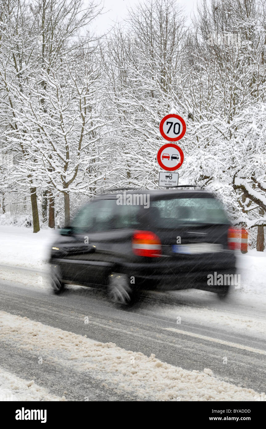 Car on a snow-covered road in winter, slip hazard, warning sign, prohibition sign, blur Stock Photo