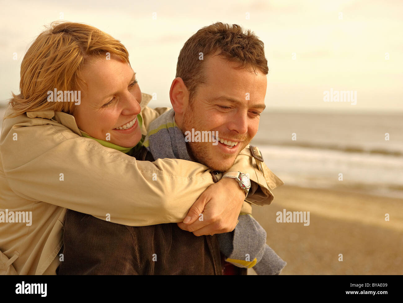 Woman embracing man from behind on beach Stock Photo - Alamy