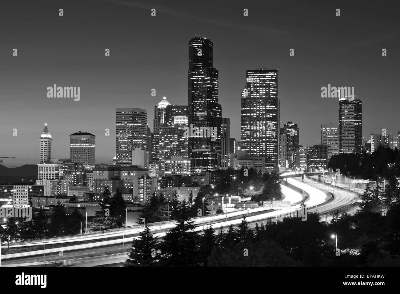 Black and white, night shot, city highway Interstate 5 in front of the skyline of the Financial District with Columbia Center Stock Photo