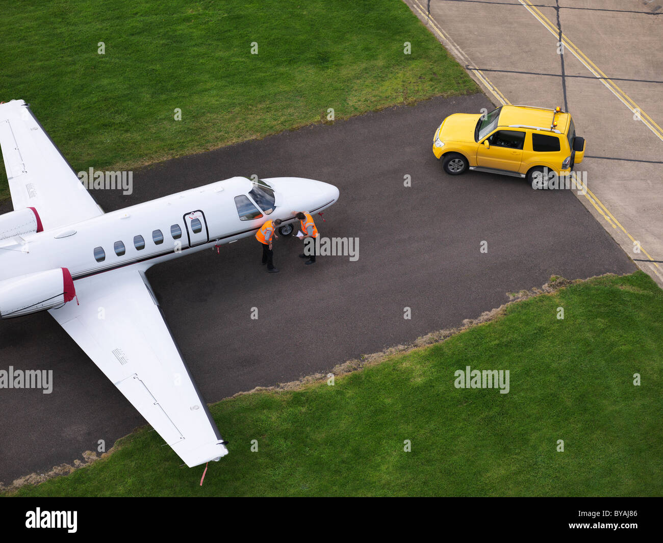 Engineers inspect jet on runway Stock Photo