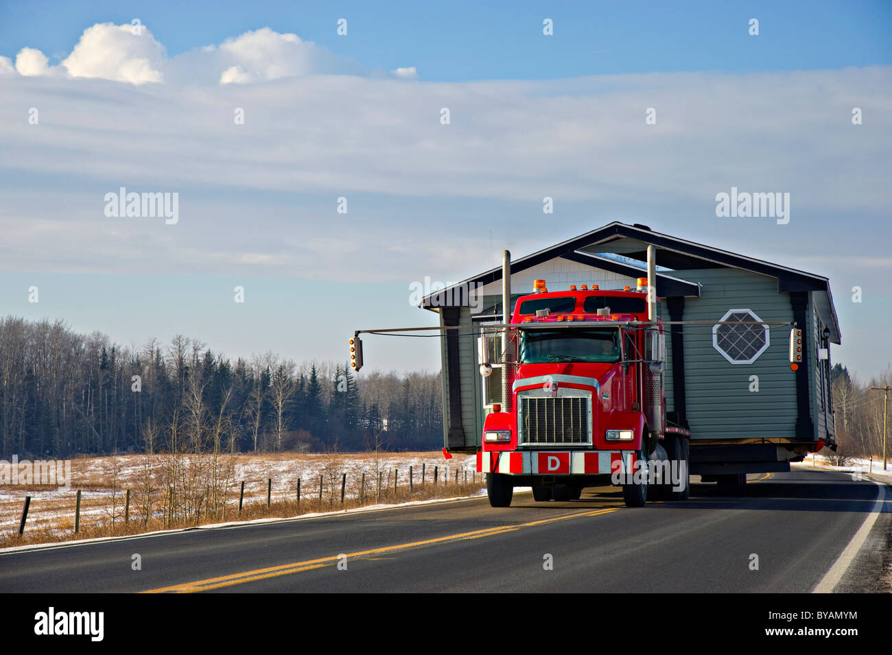 A tractor trailer truck moving a house Stock Photo
