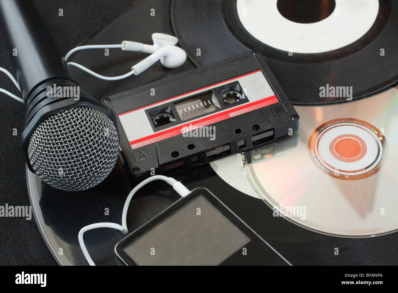 Microphone, vinyl discs, audiotape, mp3 player, cd over black Stock