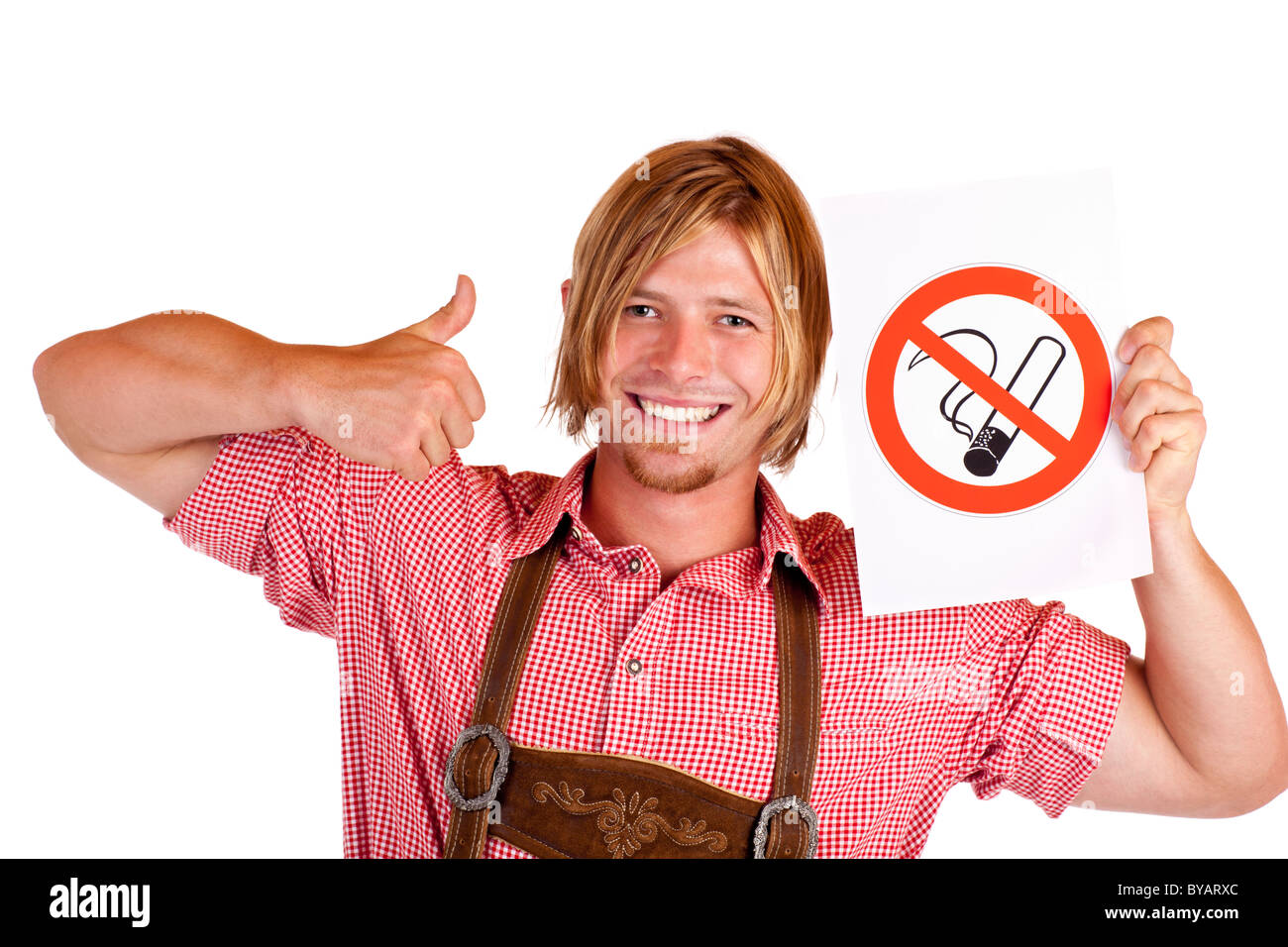 Smiling Bavarian man in lederhose holds no-smoking-rule sign. Isolated on white background. Stock Photo