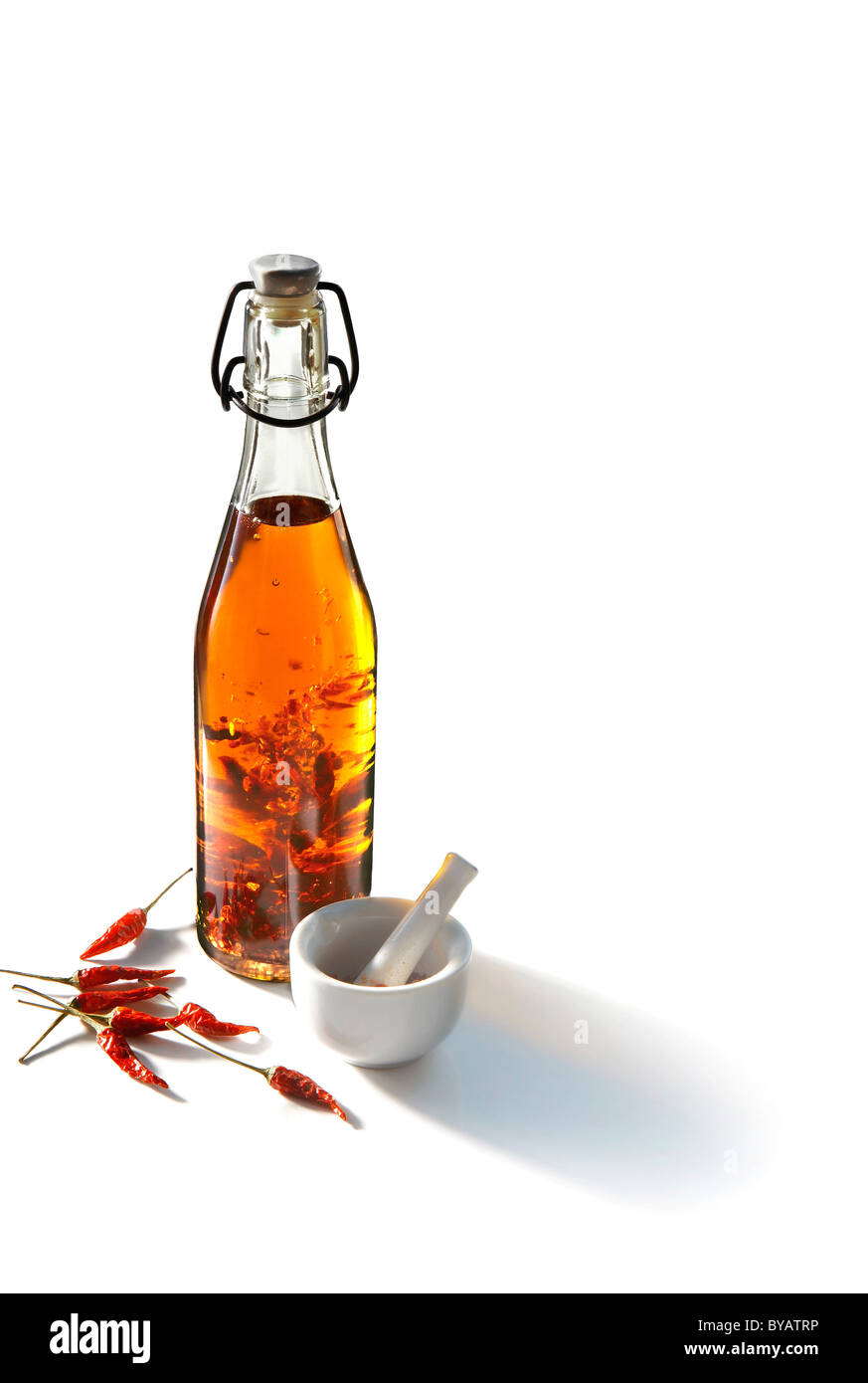 Chili oil with chilies in a bottle beside a mortar Stock Photo Alamy