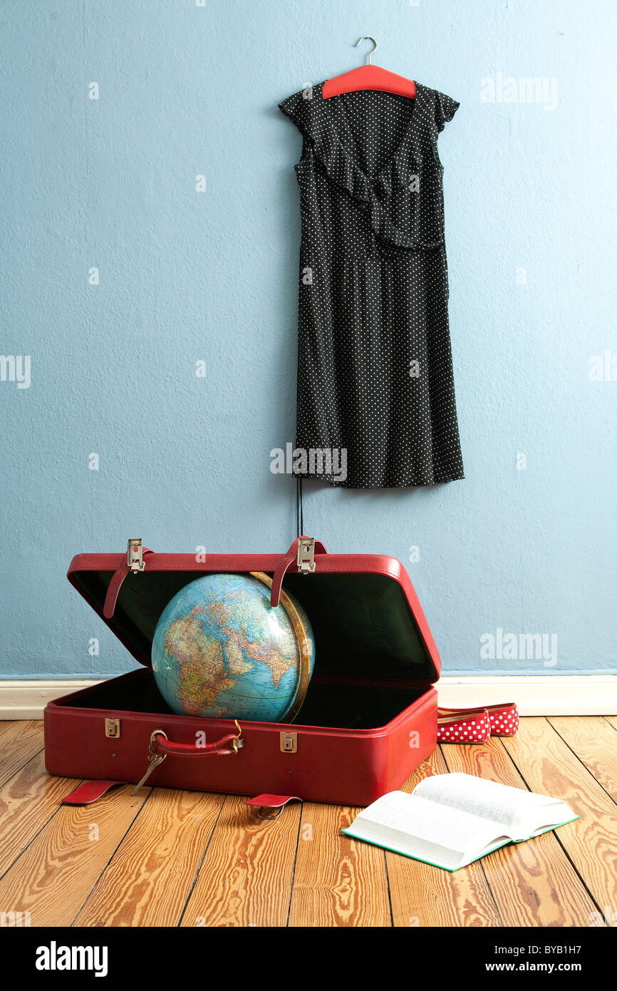 Globe in a suitcase, dress hanging on a clothes hanger, book, symbolic