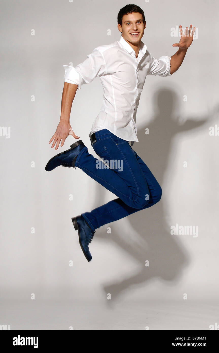 Young man in white shirt and blue jeans jumping Stock Photo - Alamy