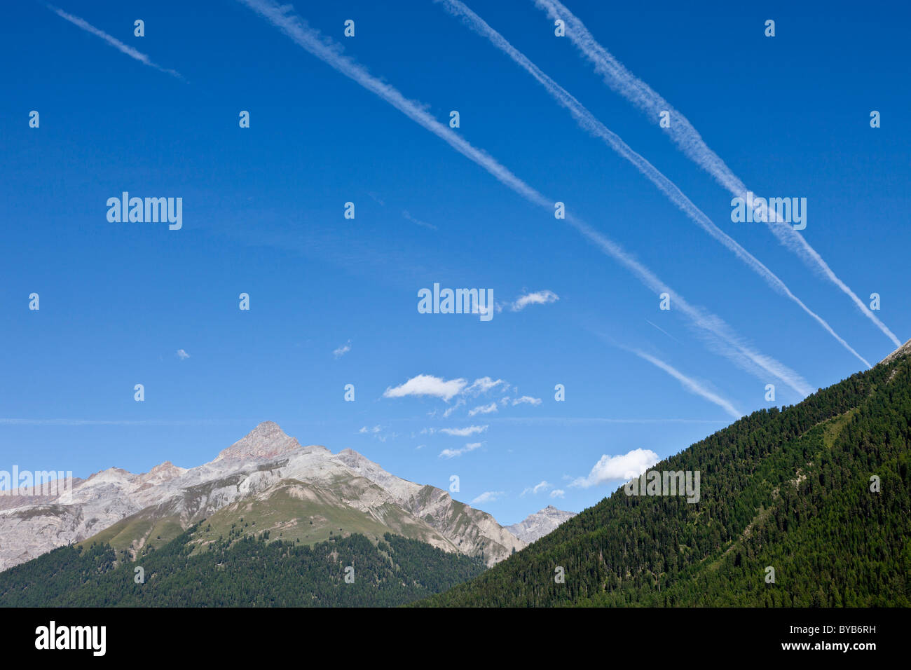 Mountain landscape with vapour trails from aircraft in the blue sky, Zuoz, Graubuenden or Grisons, Switzerland, Europe Stock Photo