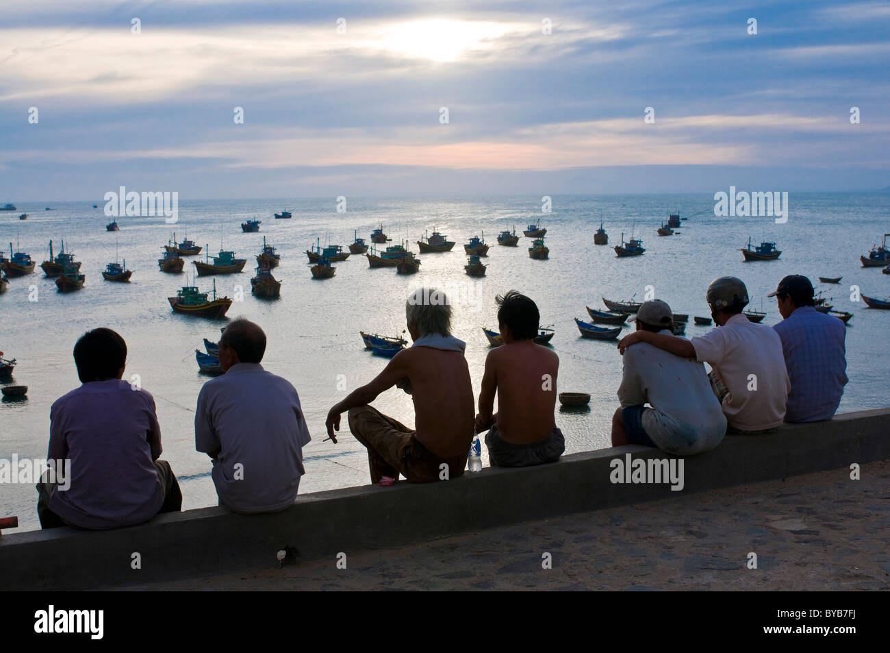 Menschen betrachten den Hafen von Mui Ne in der Daemmerung, Vietnam, Asia Stock Photo