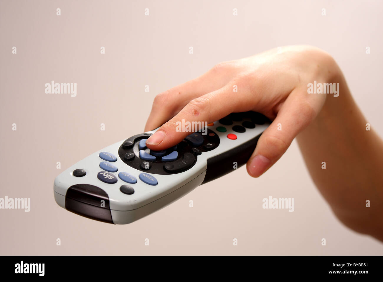 A close up of a Sky television TV remote control held by a white