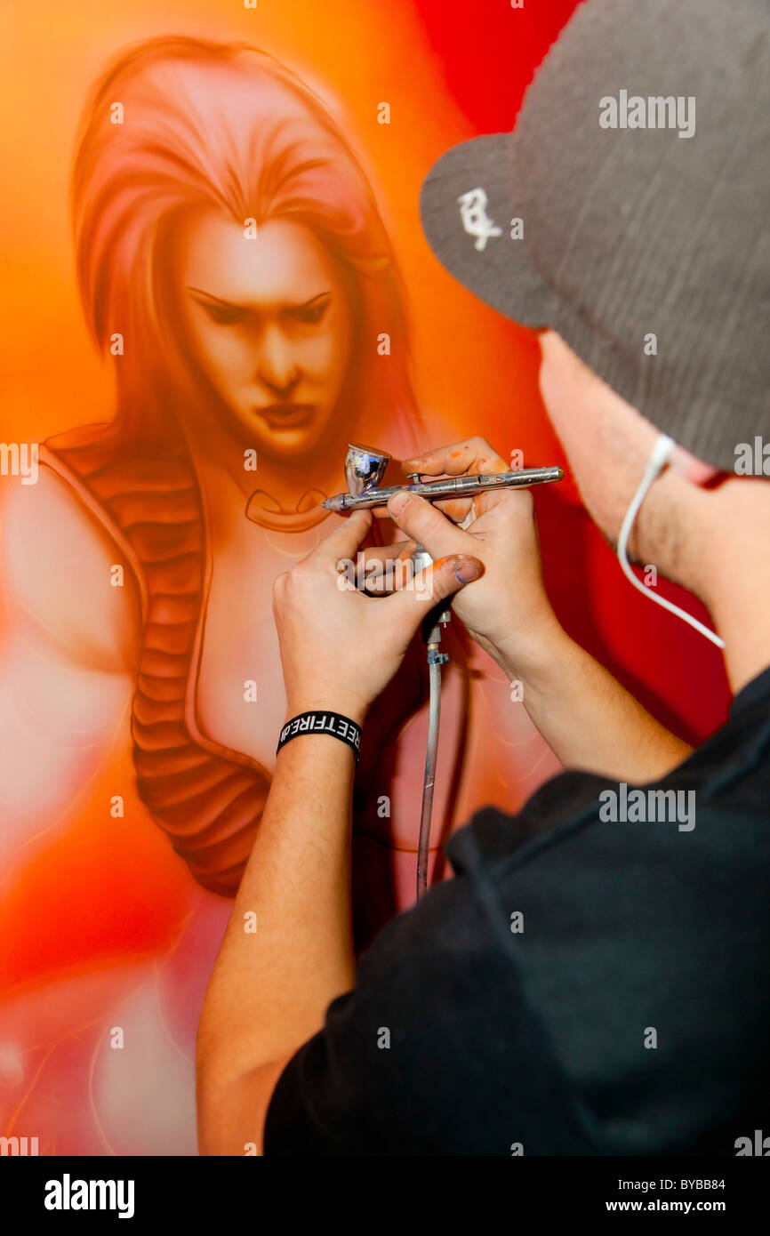 Man airbrushing art onto a car bonnet Stock Photo