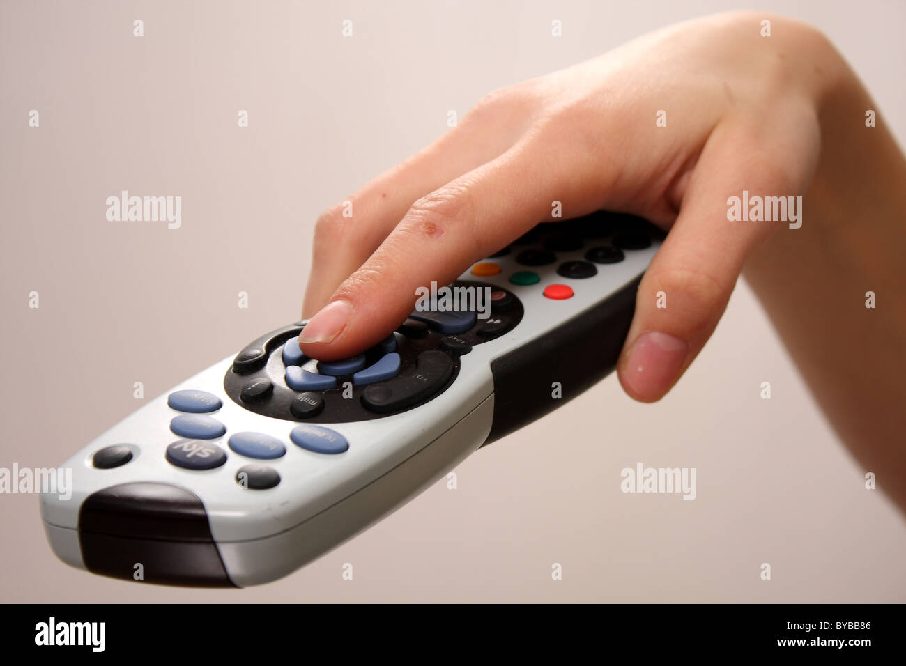 A close up of a Sky television TV remote control held by a white