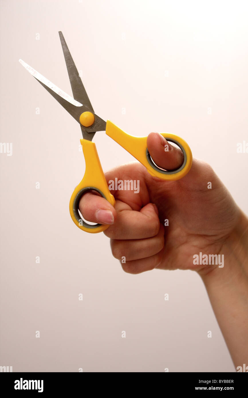 A white Caucasian female holding a pair of sharp yellow scissors used