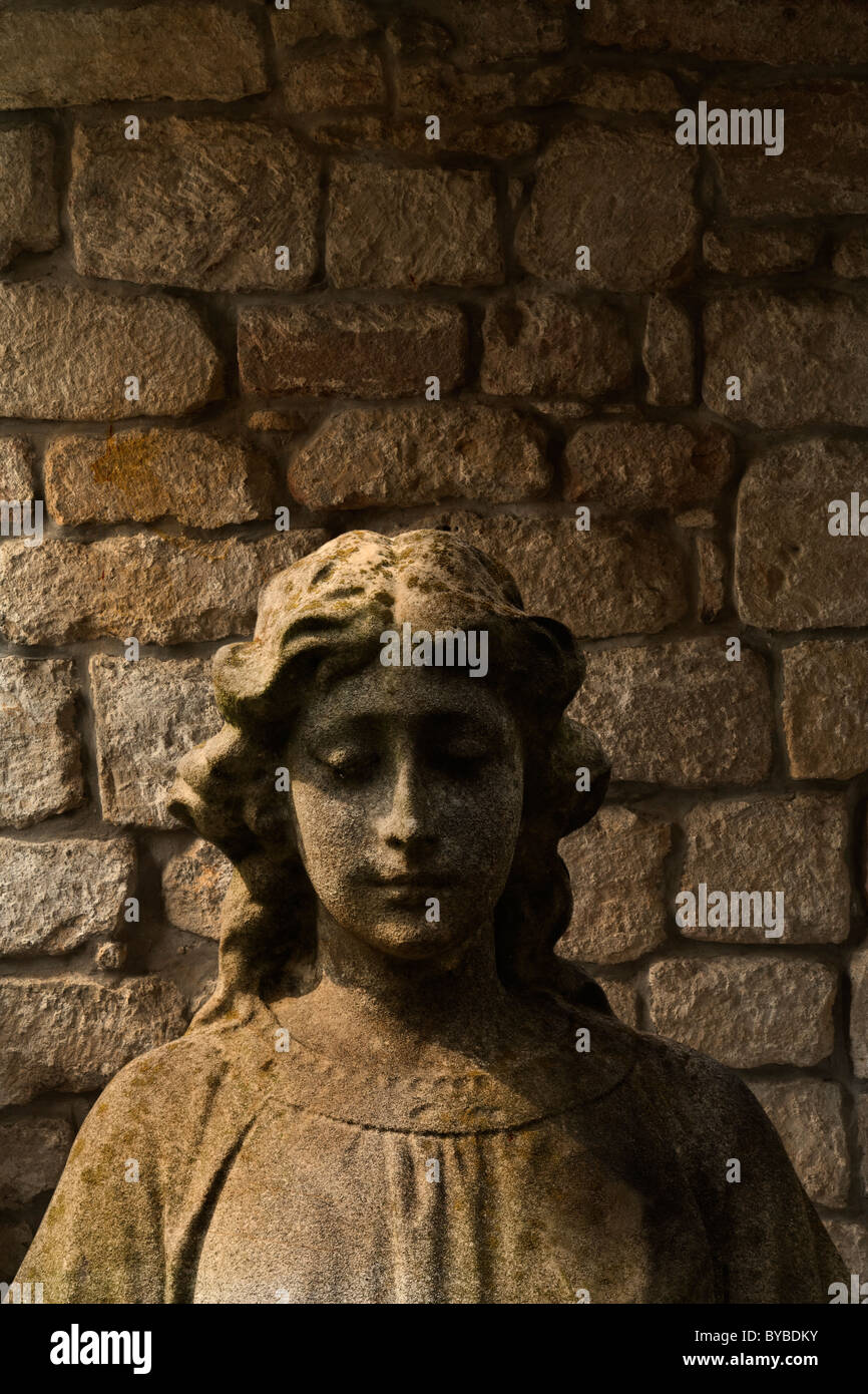 A stone woman statue standing in front of a rustic stone wall Stock Photo Alamy