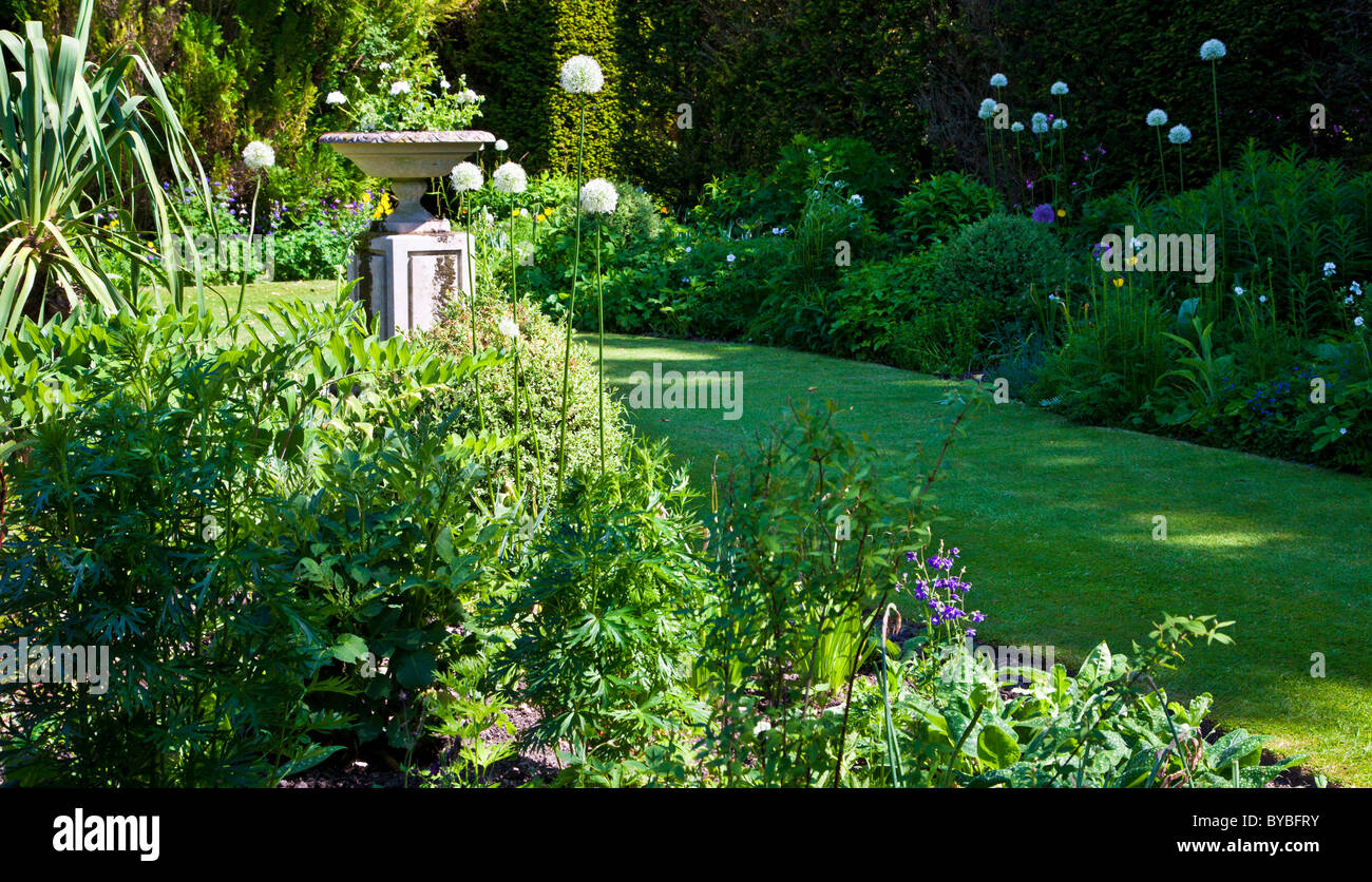 A small lawn in an English country garden in summer with a stone planter on a plinth. Larger version available BYBFP5 Stock Photo
