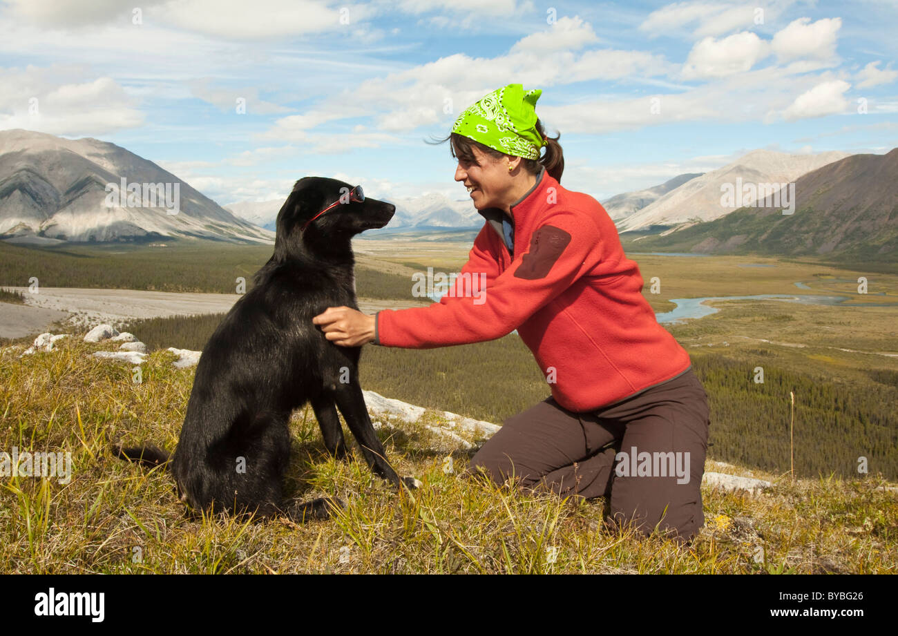 Young woman playing with her dog, Alaskan Husky, sled dog, enjoying the view, panorama, Wind River valley and Mackenzie Stock Photo