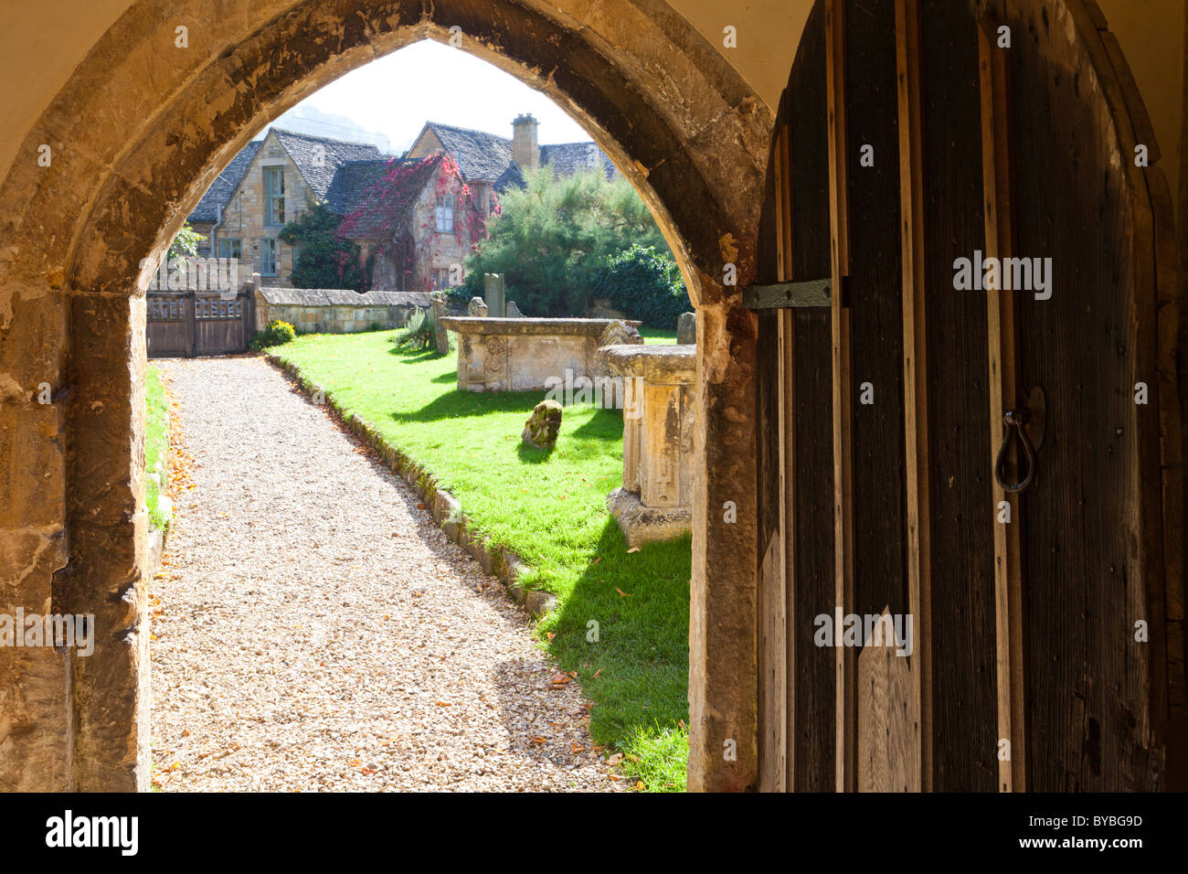 Looking up the churchyard path from the porch doorway of St Michaels church in the Cotswold village of Stanton, Gloucestershire Stock Photo