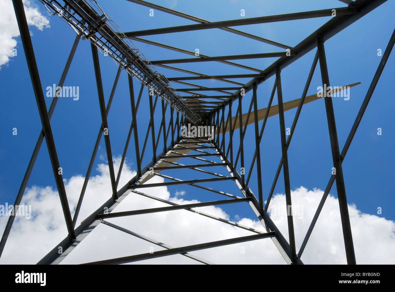 Wind turbine trellis viewed from bottom against blue and white sky Stock Photo