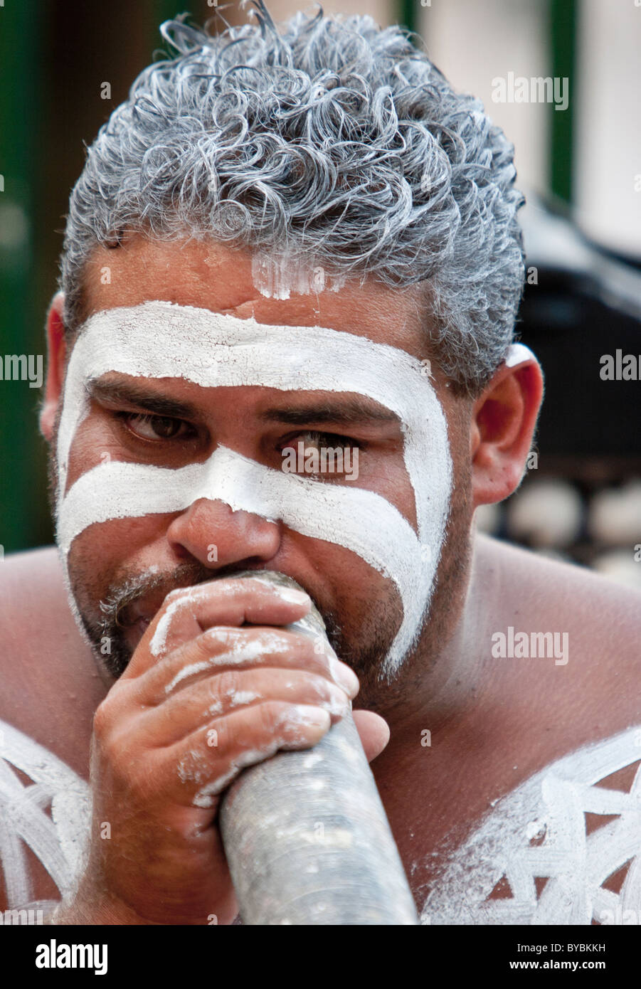 Didgeridoo player with traditional body paint performing in the street at Sydney Stock Photo