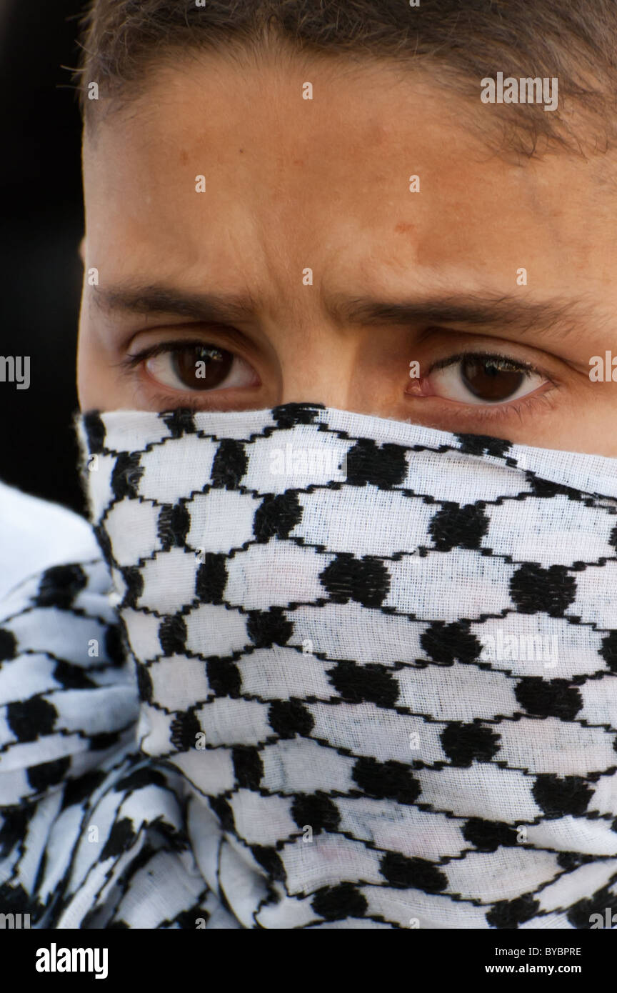 His face covered by a keffiyeh, a Palestinian boy marches with activists protesting Jewish settlements in East Jerusalem Stock Photo