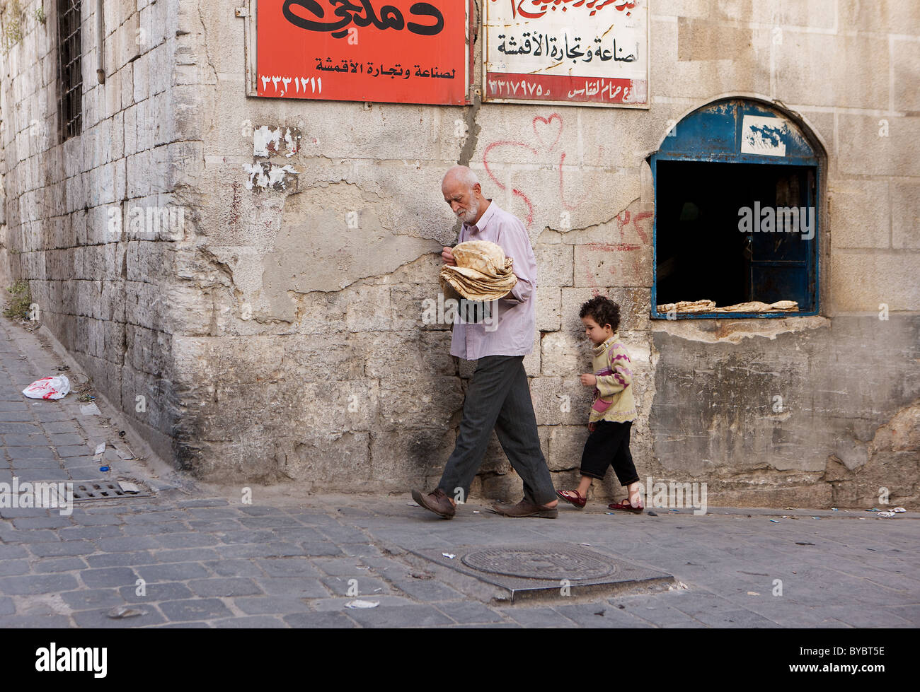 Collecting the daily bread from a traditional back street bakery in Old City of Aleppo, Syria Stock Photo