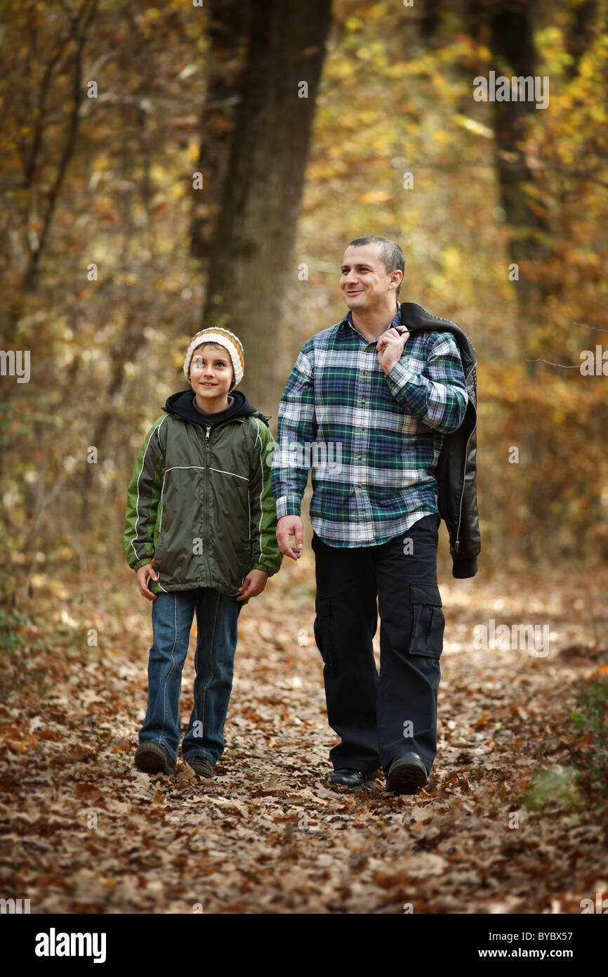 Father and son talking a walk outdoor in a forest, in an autumn day ...