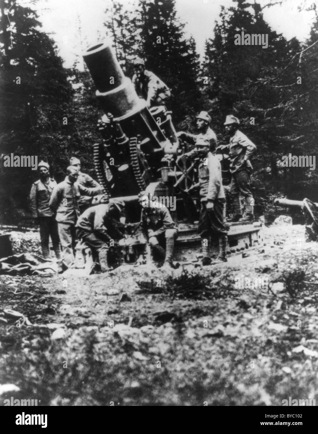 Soldiers gathered around a large cannon or howitzer mounted to a base. Stock Photo