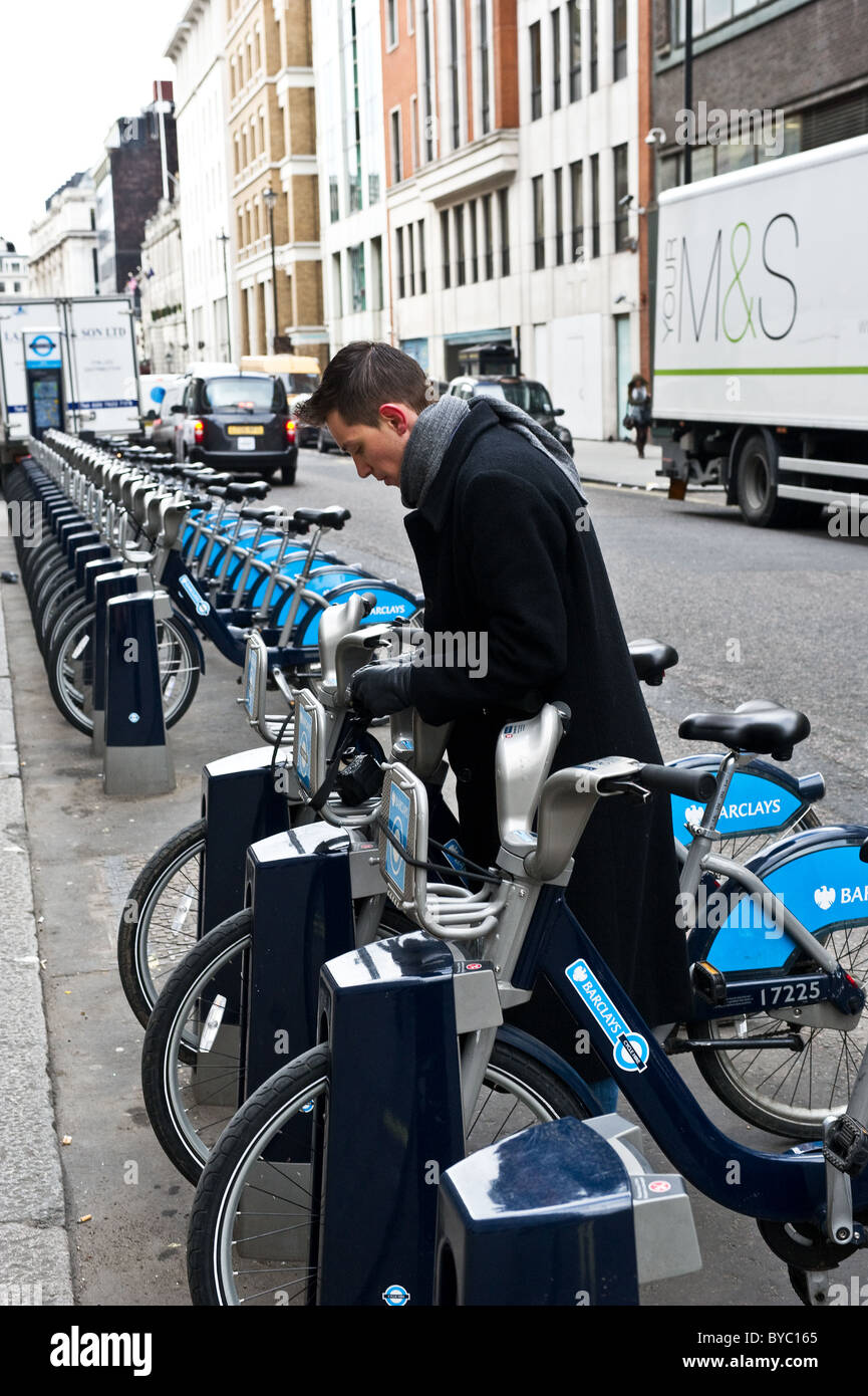 A commuter unlocking a hire bicycle in London. Stock Photo