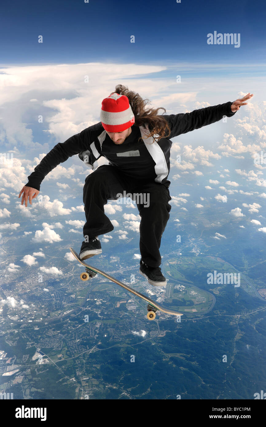Skateboarder high above the clouds performing a trick Stock Photo