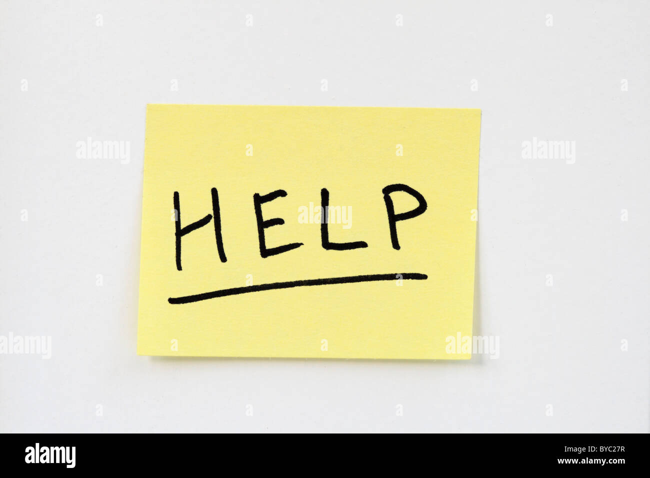 help written in black ink on a small yellow sticky note stuck on a white wall Stock Photo