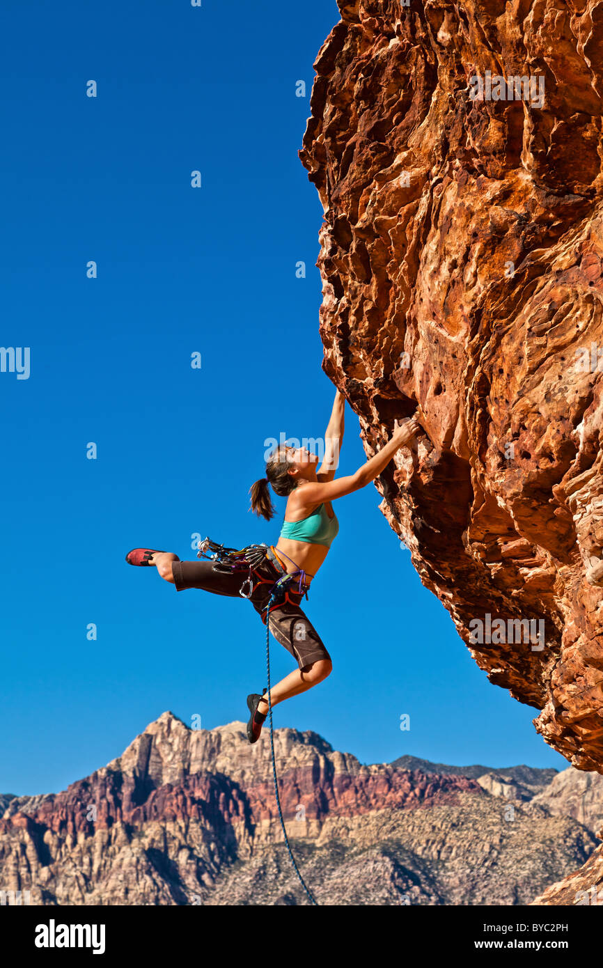 Female rock climber struggles for her next grip dangling on the edge of ...