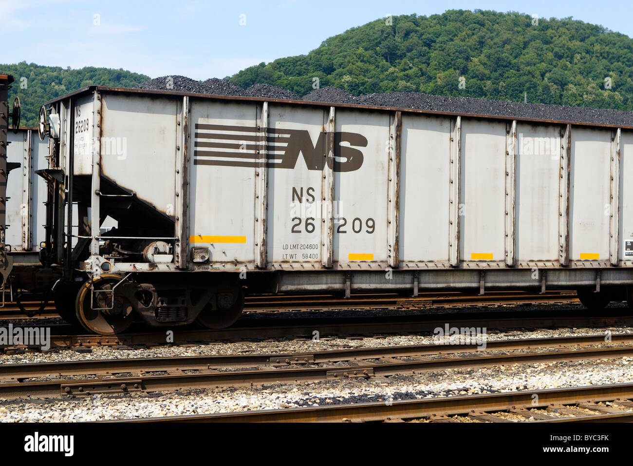 One Norfolk Southern coal car in the middle of a train of coal car gondolas. Taken in the Dickinson, WV rail yard in the summer. Stock Photo