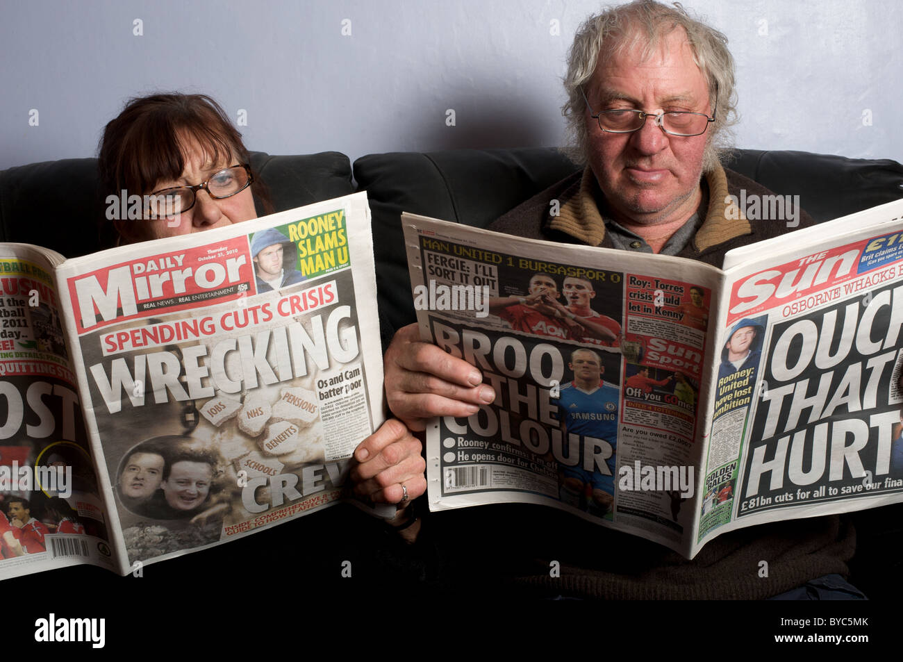 Married couple reading The Daily Mirror and The Sun British tabloid newspapers Stock Photo