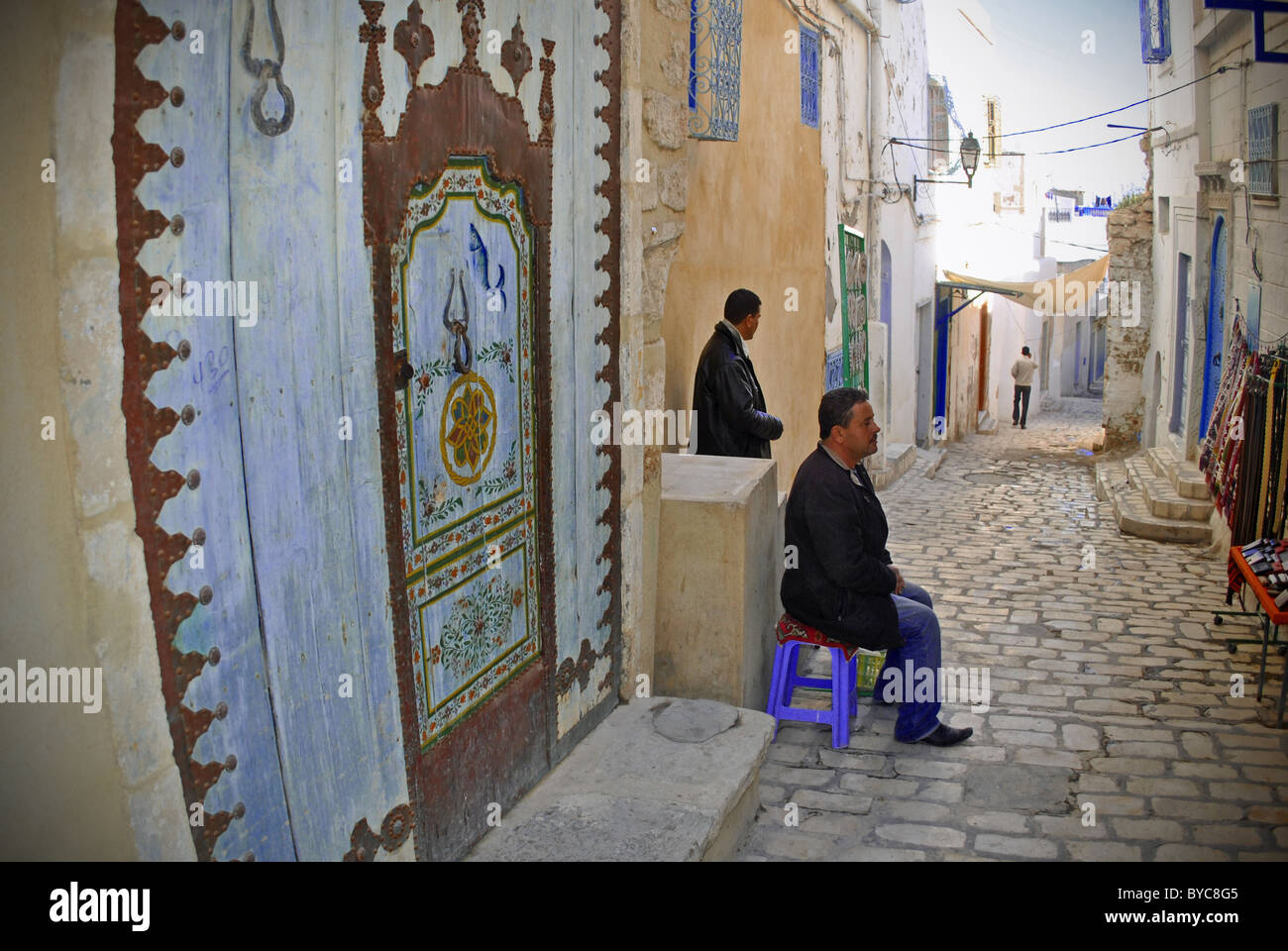 Street scene in Sousse Medina with men sitting and colorful door, Tunisia Stock Photo