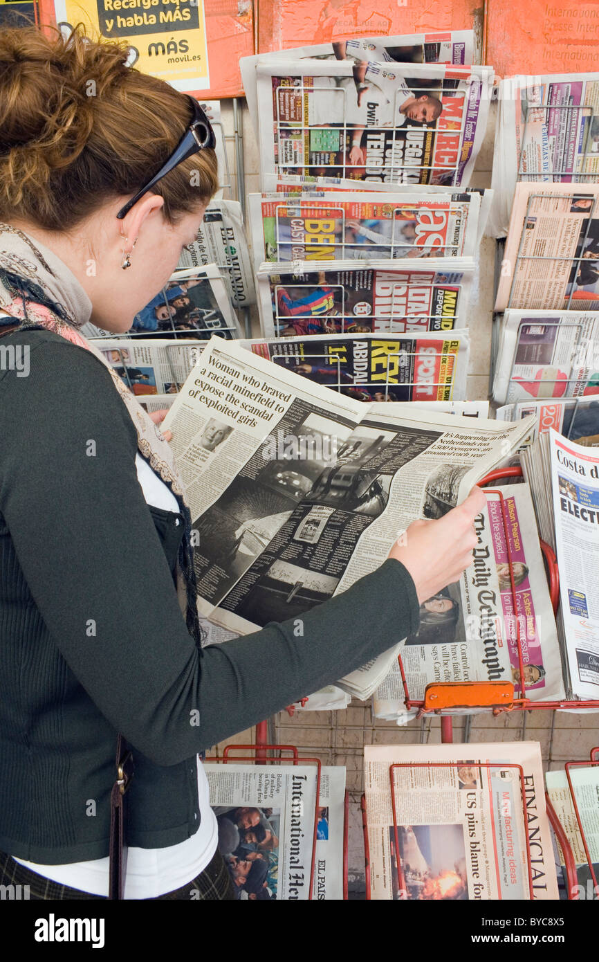 Young woman reading newspaper outside shop in Fuengirola, Spain. Stock Photo