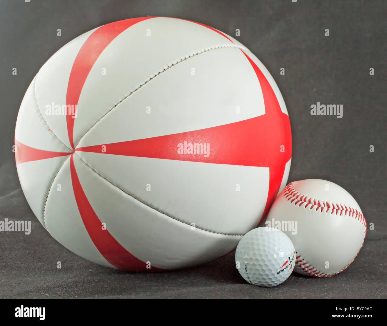Three different balls for rugby, golf and baseball over black Stock