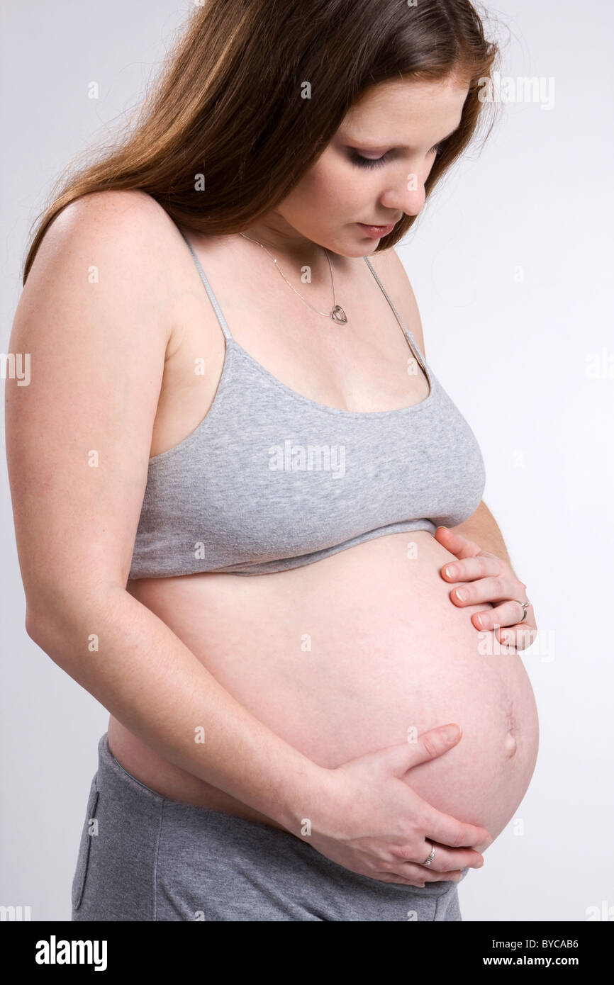 A young expectant woman ponders her pregnancy and her soon to arrive baby. Stock Photo