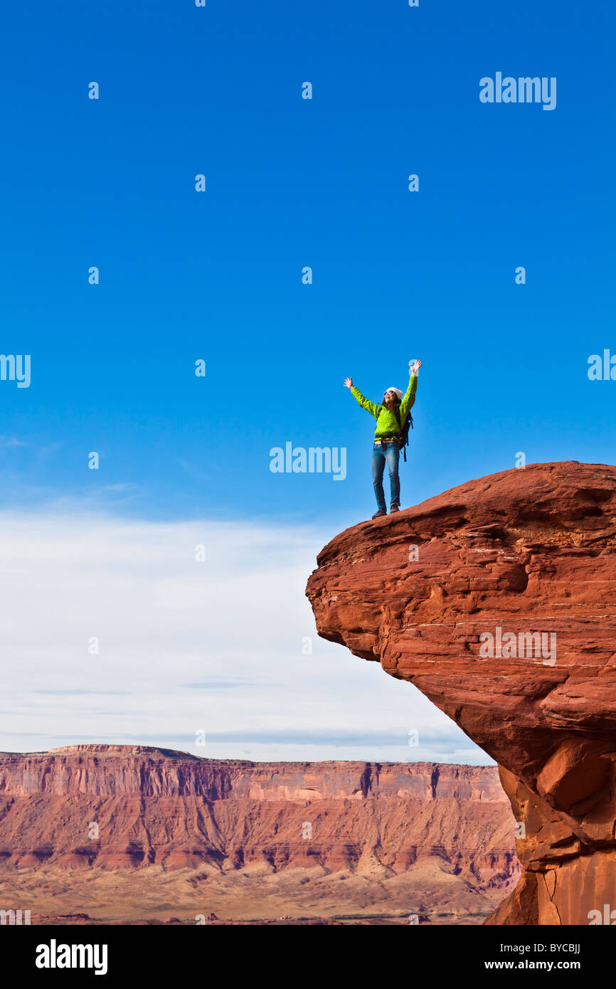 Hiker on the summit of a sandstone spire in Canyonlands National Park. Stock Photo