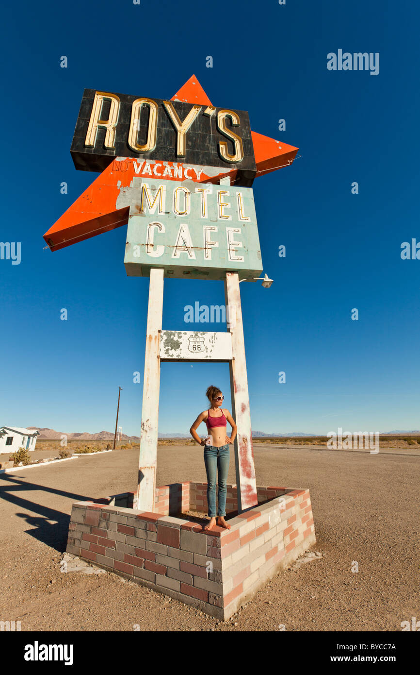 Attractive, young woman being silly at an abandoned roadside motel sign. Stock Photo