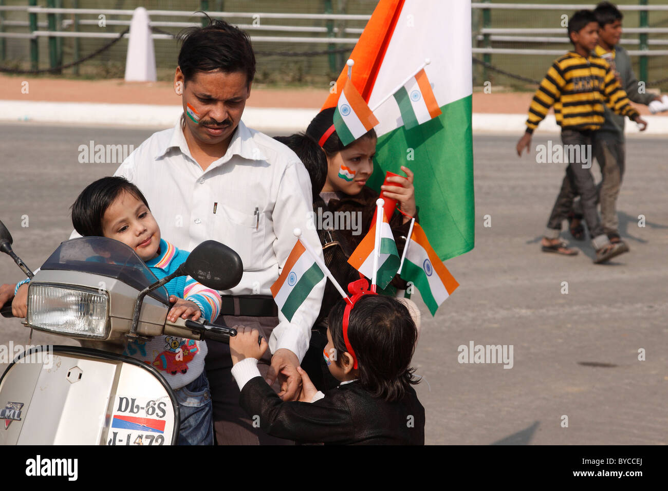 Family riding two-wheeler scooter kids holding Indian tricolor national flag Republic Day 26th January Rajpath New Delhi India Stock Photo