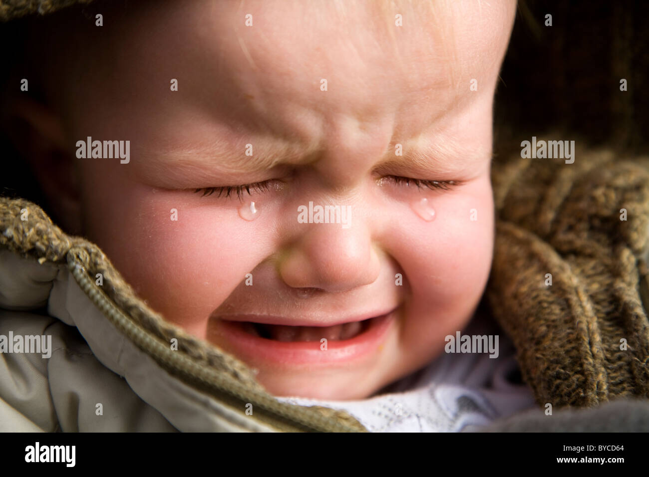 Face of an unhappy baby (young toddler) cry / crying / cries / scream / screaming. Stock Photo