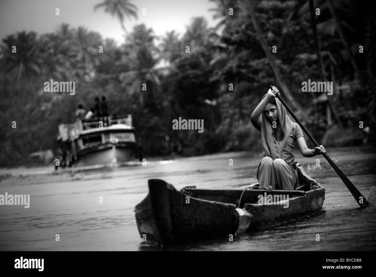 A woman crosses a river in a traditional wooden canoe in the backwaters near Alappuzha (a.k.a. Alleppey) in Kerala, India. Stock Photo