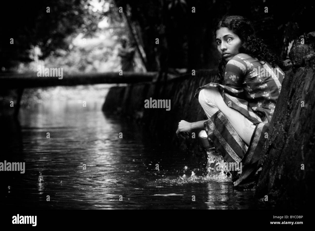 A woman washes dishes in the backwaters near Alappuzha (a.k.a. Alleppey) in Kerala, India. Stock Photo