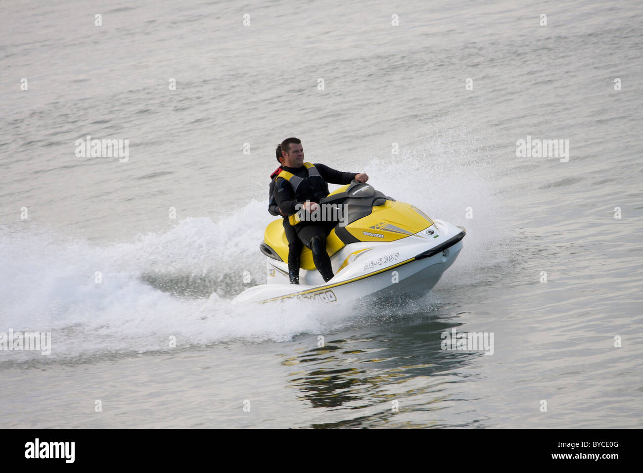 Two people on a jet ski; jet skiing on a cold day through in wet suits