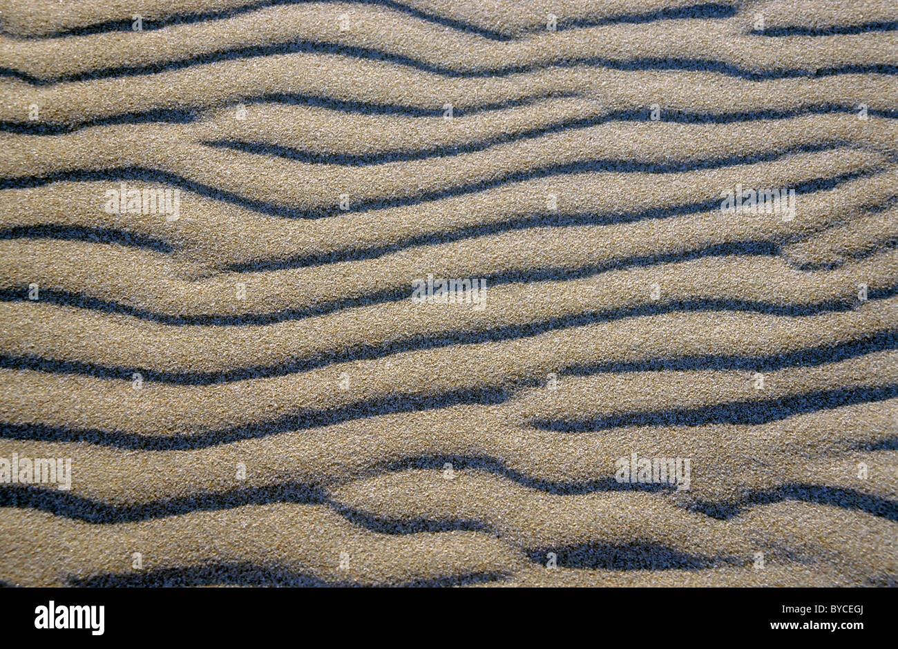 Patterned waves in white sand in the evening. Stock Photo