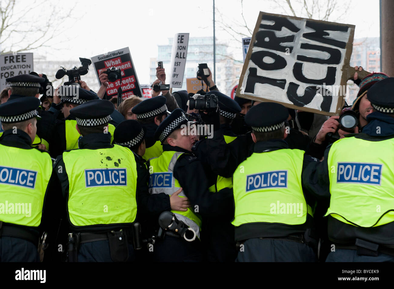 A march to protest government cuts in education spending. At Millbank Tower they are met by a long cordon of riot policemen. Stock Photo